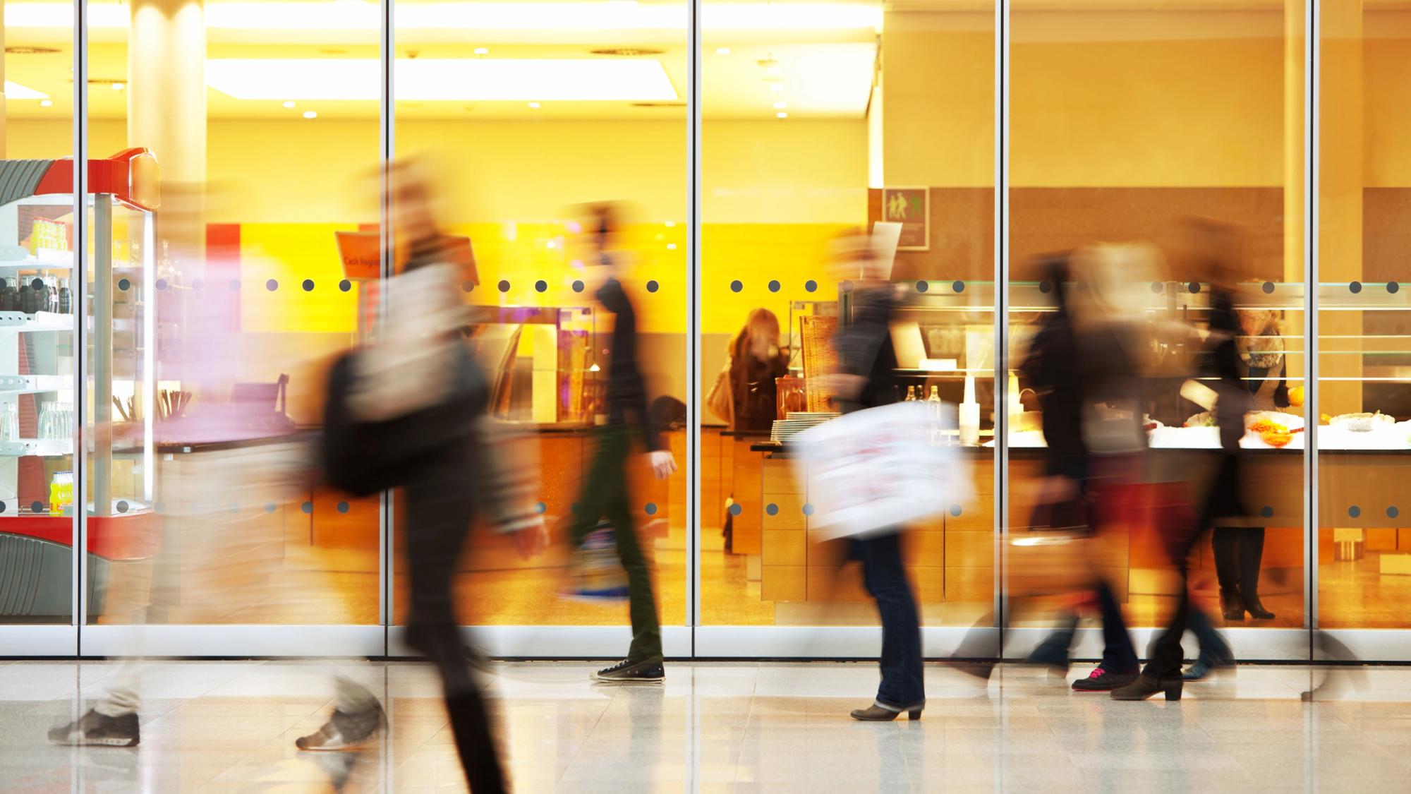 Stock image of shoppers walking in front of a lit window