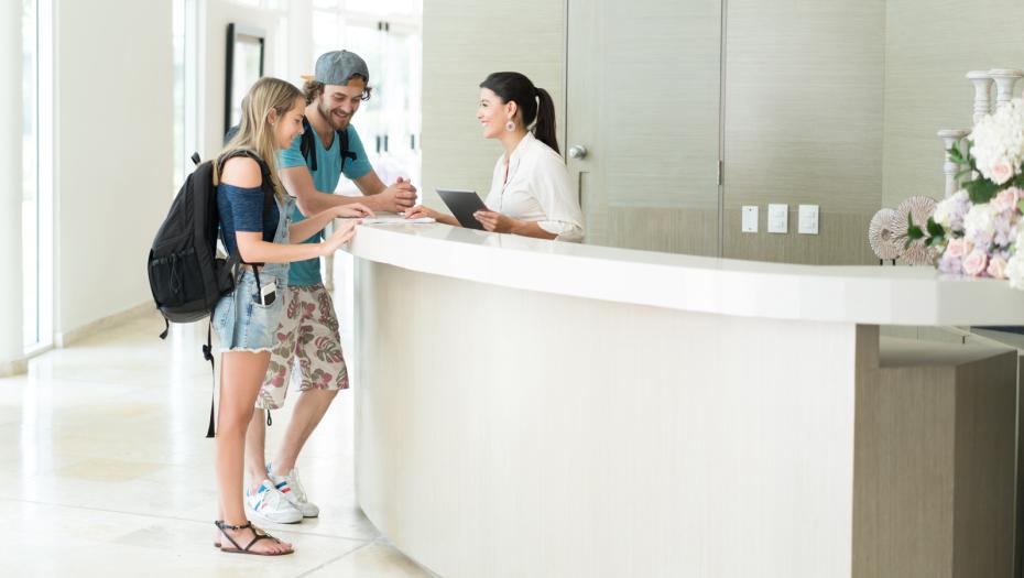 Couple checking in the reception of a hotel/hostel.